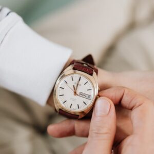 Person winding a leather wristwatch